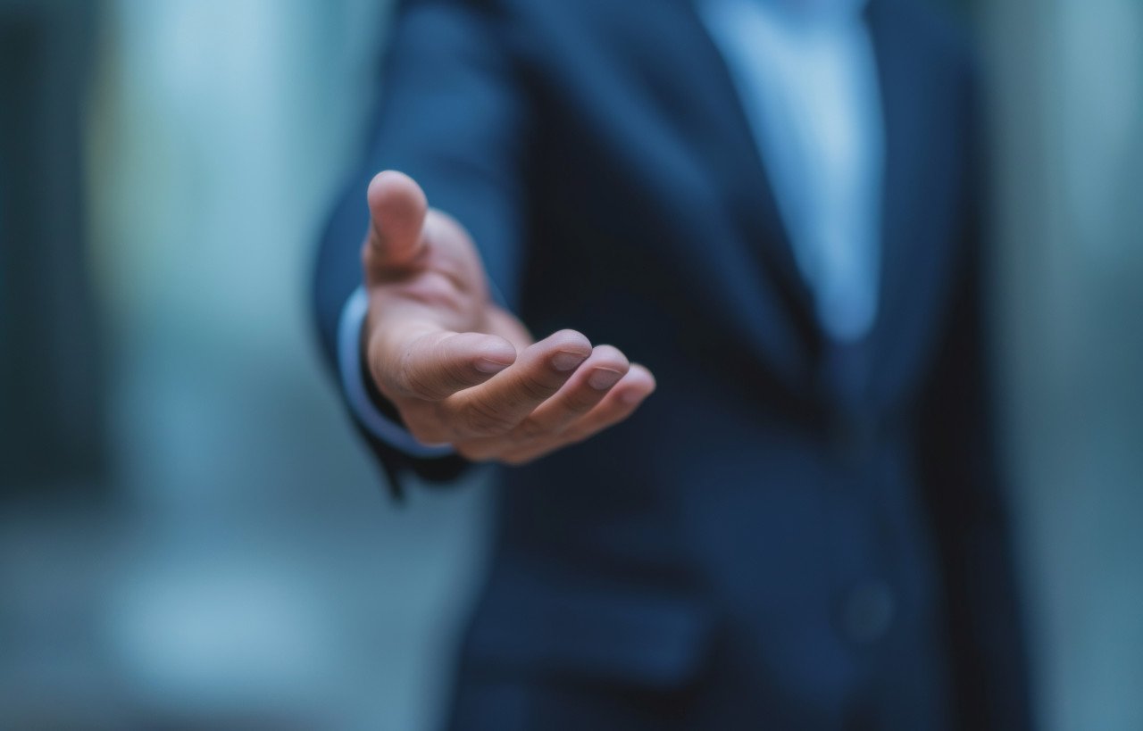 A professional showcases an open palm symbolizing trustworthiness and sincerity in business interactions
